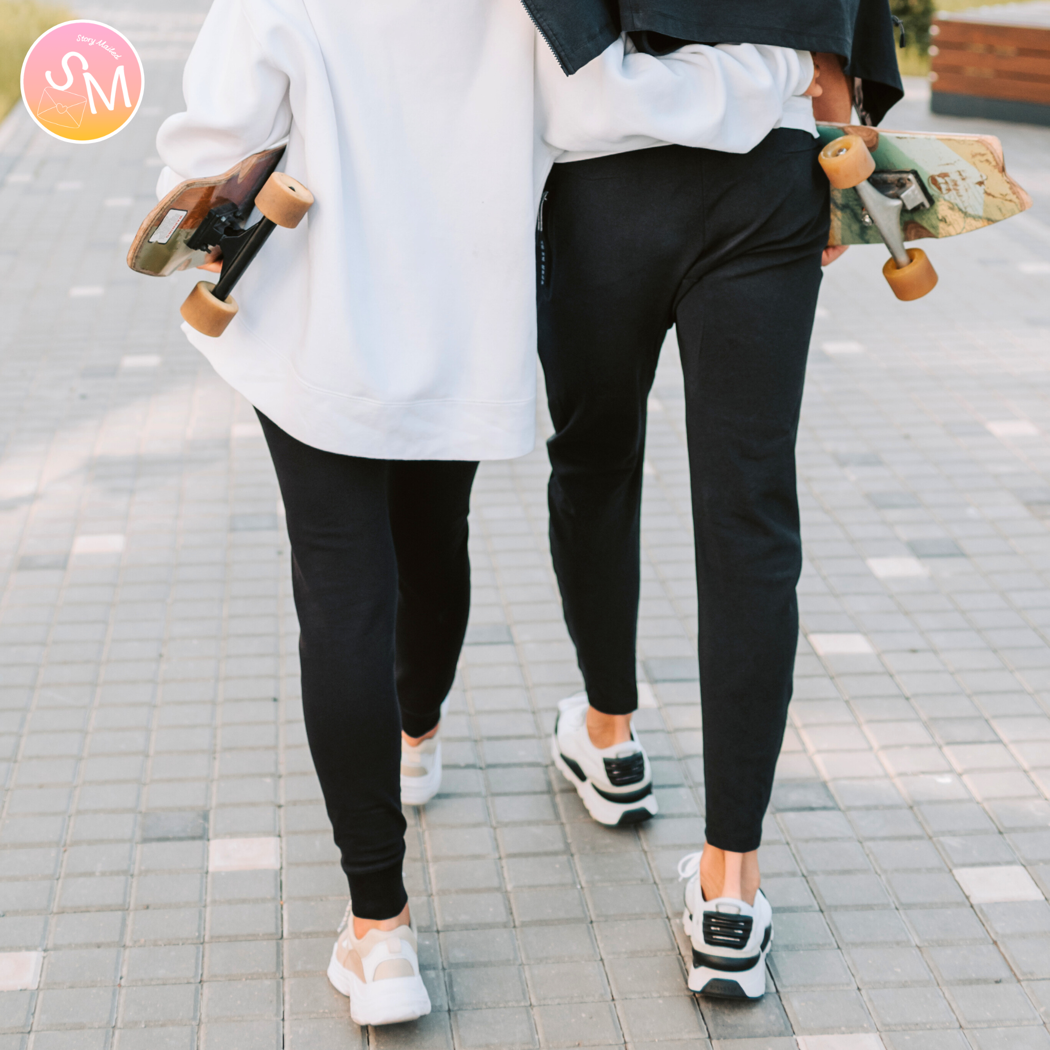 Two people holding skateboards on a tiled pavement